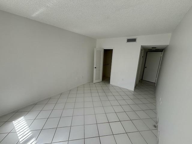 tiled empty room featuring a textured ceiling