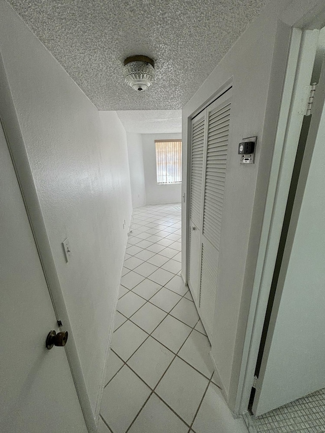 corridor featuring light tile patterned floors and a textured ceiling