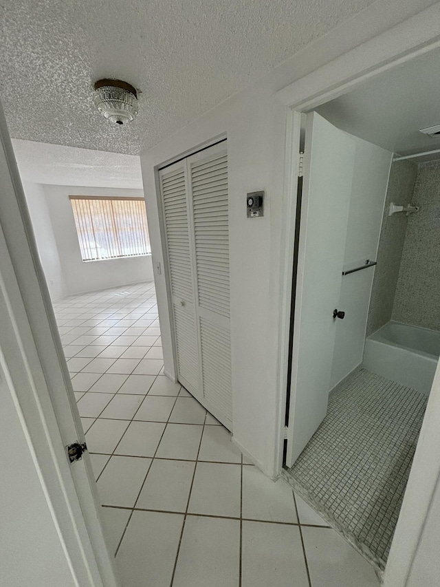 corridor with a textured ceiling and light tile patterned flooring