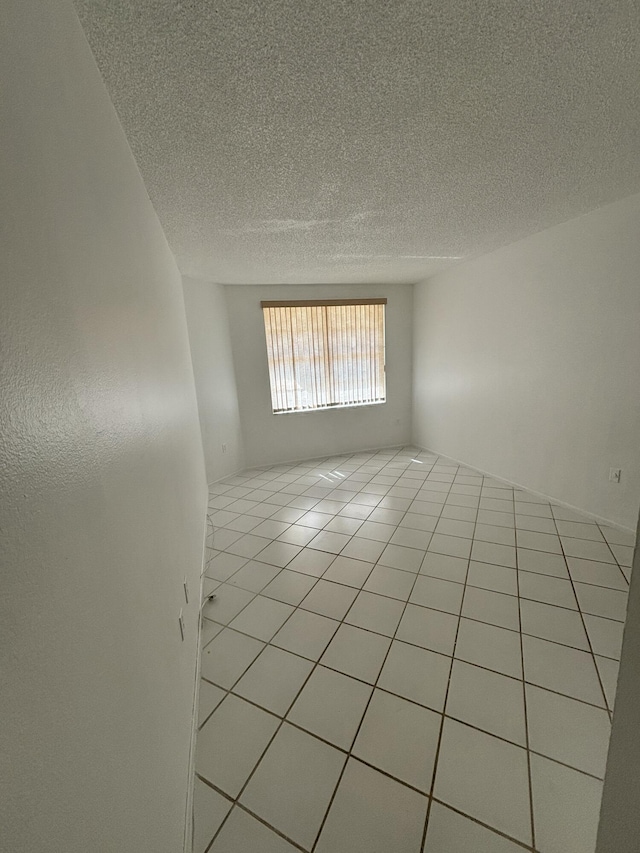tiled spare room featuring a textured ceiling