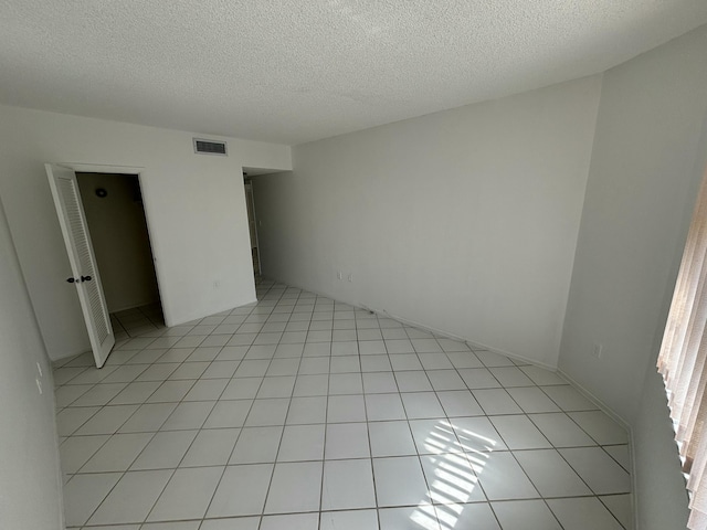 tiled empty room featuring a textured ceiling