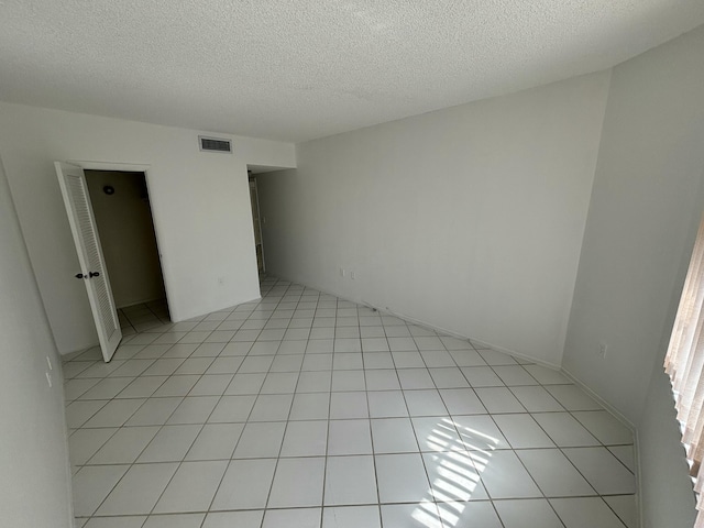 tiled empty room with a textured ceiling