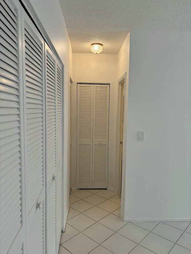 hallway featuring light tile patterned floors and a textured ceiling