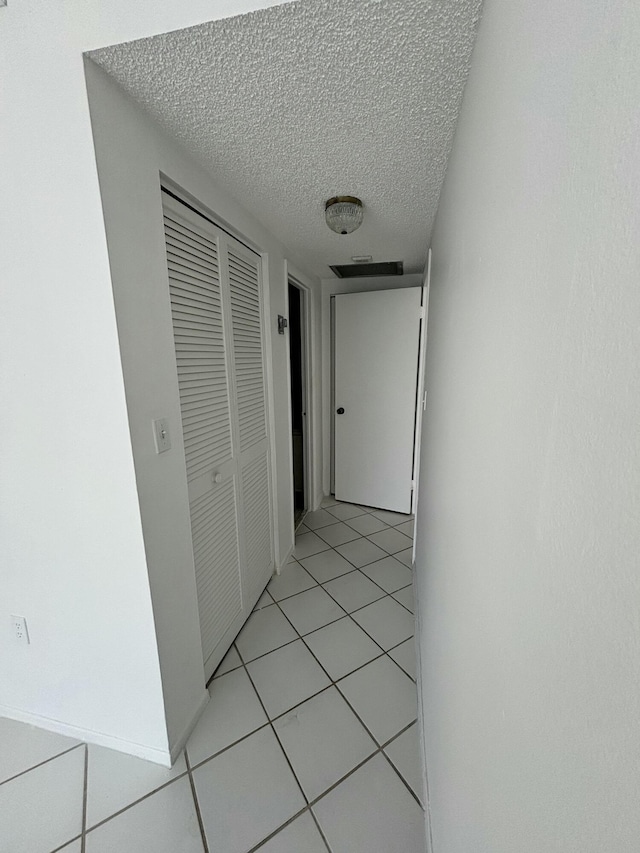 hall with light tile patterned floors and a textured ceiling