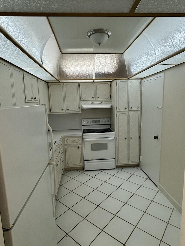 kitchen with cream cabinets, light tile patterned floors, and white appliances