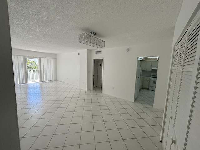 tiled empty room featuring a textured ceiling