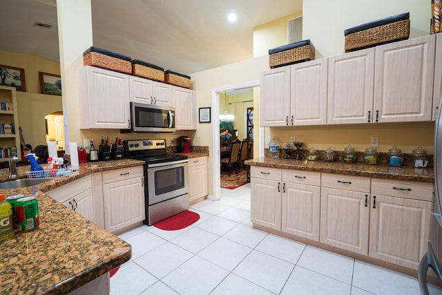 kitchen featuring light tile patterned flooring, sink, white cabinets, dark stone counters, and stainless steel appliances