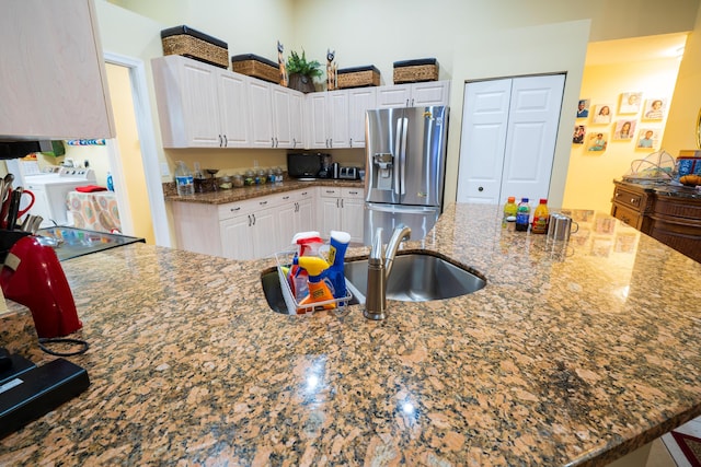 kitchen featuring white cabinetry, stone countertops, washer and clothes dryer, and stainless steel fridge with ice dispenser