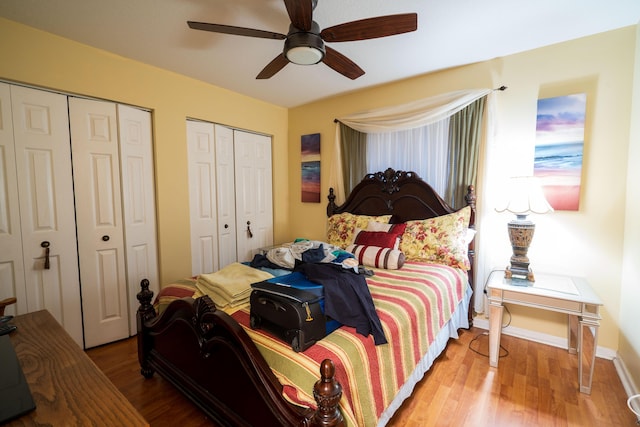 bedroom with ceiling fan, wood-type flooring, and multiple closets