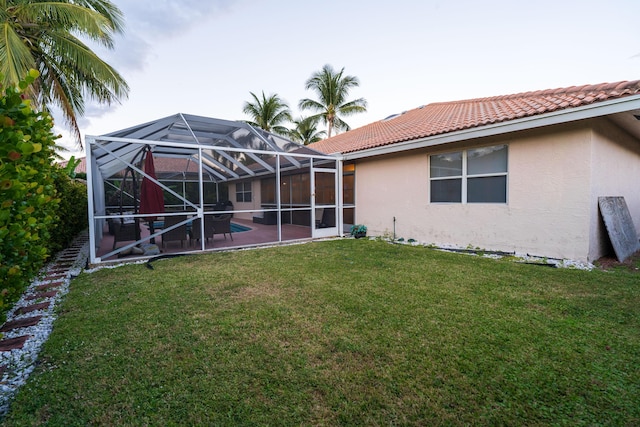 back of house with a patio, a yard, and glass enclosure