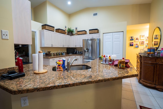 kitchen with sink, stainless steel fridge, white cabinetry, light tile patterned flooring, and kitchen peninsula