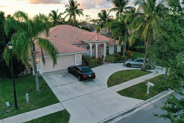 165 Cypress Trce, Royal Palm Beach, FL 33411 - mediterranean / spanish house with driveway, a tiled roof, an attached garage, and a lawn