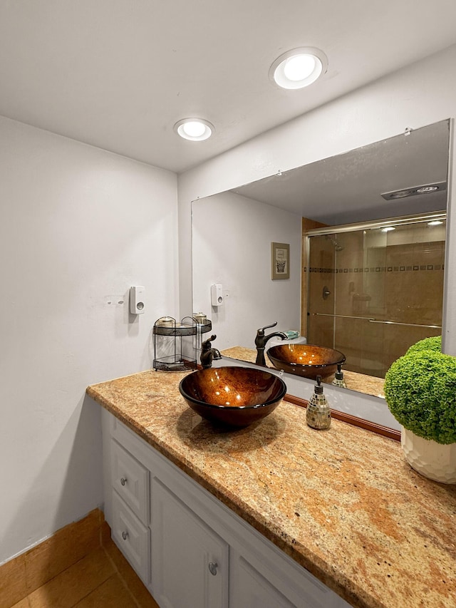 bathroom featuring vanity, a shower with shower door, and tile patterned flooring