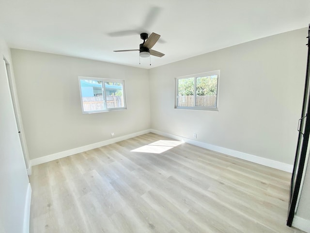 empty room featuring ceiling fan, a healthy amount of sunlight, and light wood-type flooring