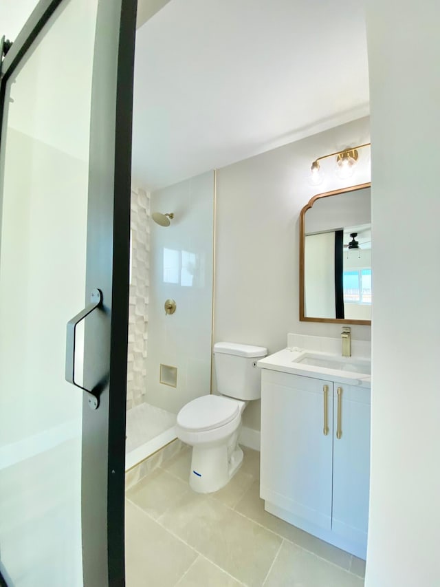 bathroom featuring vanity, tiled shower, tile patterned floors, and toilet