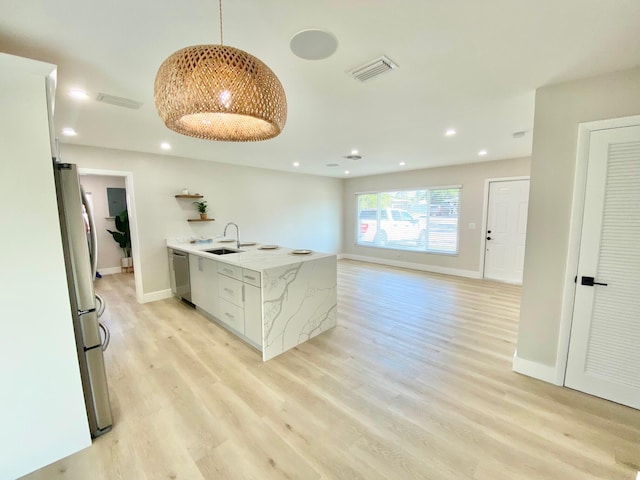 kitchen featuring sink, light wood-type flooring, pendant lighting, stainless steel appliances, and white cabinets