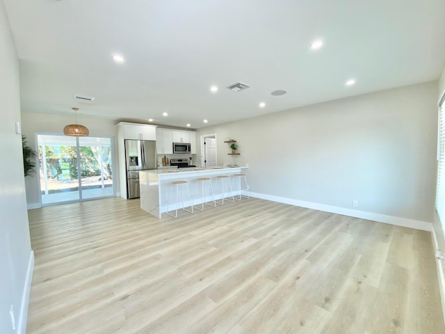 kitchen with white cabinetry, hanging light fixtures, appliances with stainless steel finishes, a kitchen breakfast bar, and kitchen peninsula