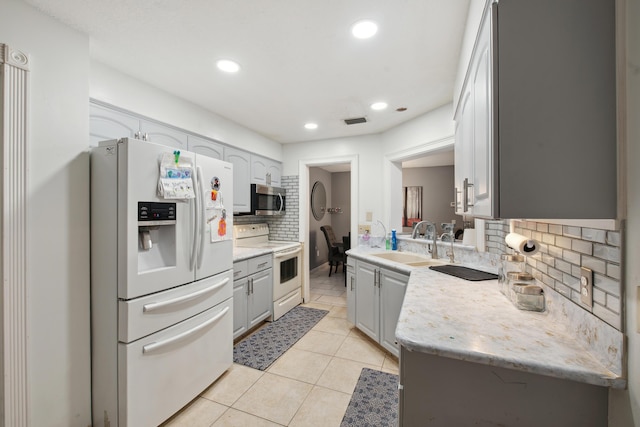 kitchen featuring light tile patterned flooring, sink, gray cabinets, white appliances, and decorative backsplash