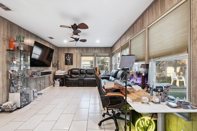 office area with light tile patterned flooring, ceiling fan, and wood walls