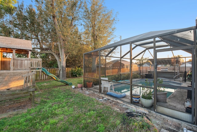 view of yard with a pool with hot tub, a playground, and glass enclosure