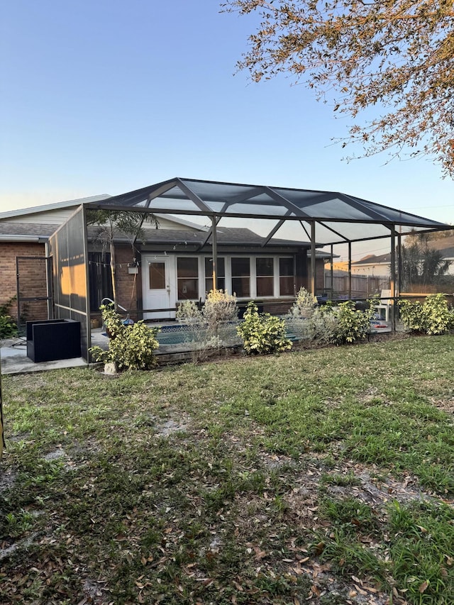 rear view of house featuring cooling unit, a lanai, and a lawn