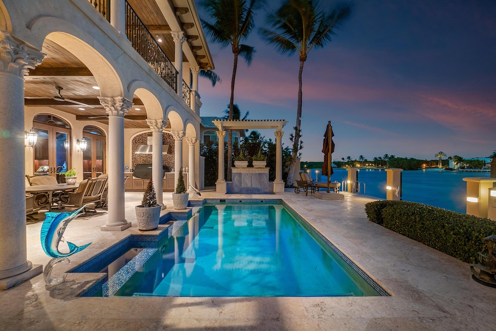 pool at dusk featuring a pergola, a patio, and a water view