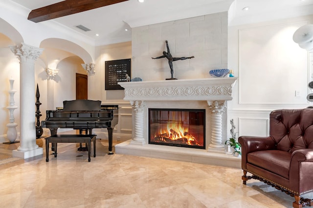 living area with beamed ceiling, a large fireplace, crown molding, and decorative columns