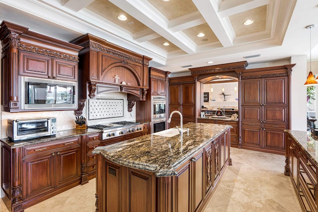 kitchen featuring sink, black microwave, pendant lighting, stainless steel gas stovetop, and a kitchen island with sink