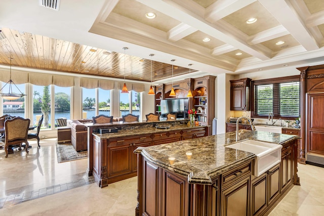 kitchen with hanging light fixtures, a kitchen island with sink, and sink