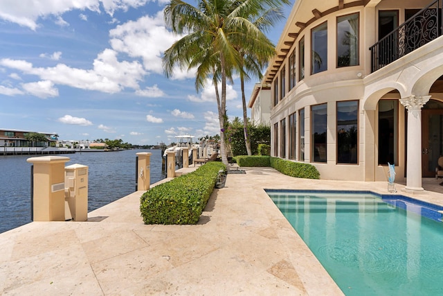 view of pool featuring a dock, a patio, and a water view