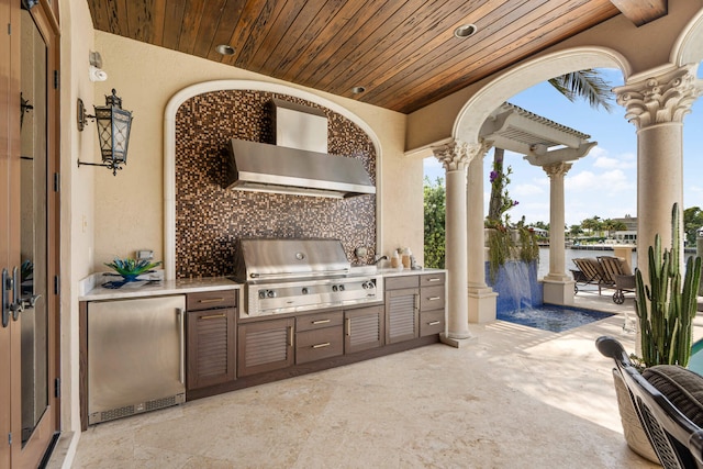 view of patio / terrace with a water view, an outdoor kitchen, and area for grilling