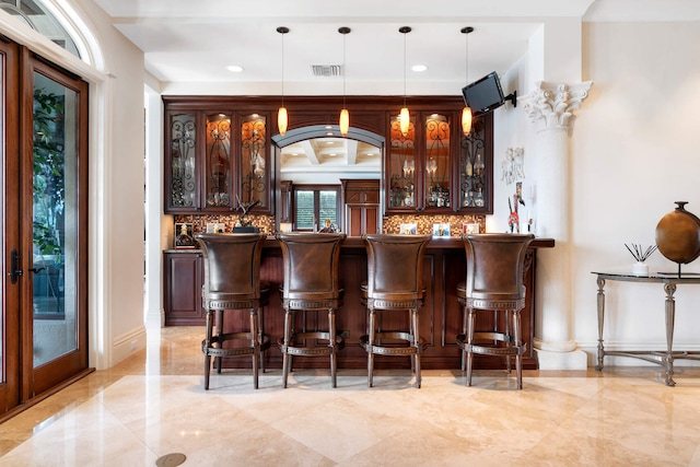 bar with dark brown cabinetry, decorative light fixtures, and french doors