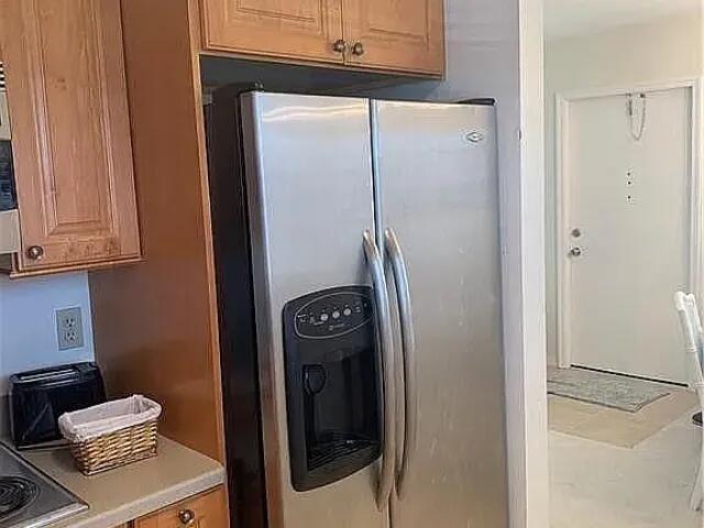 kitchen featuring light countertops, brown cabinets, and stainless steel refrigerator with ice dispenser