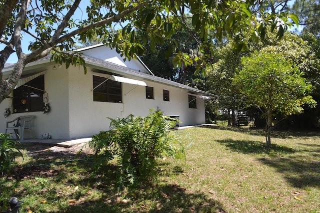 view of side of home with stucco siding and a yard