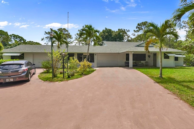 single story home featuring asphalt driveway, an attached garage, a front yard, and roof with shingles
