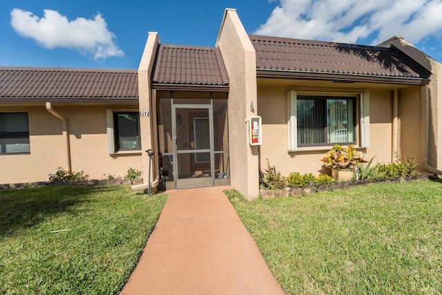 view of exterior entry with a lawn