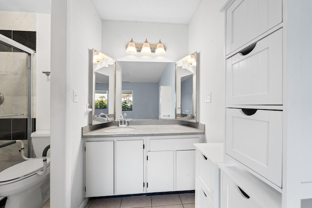 bathroom with tile patterned floors, toilet, a shower with door, and vanity