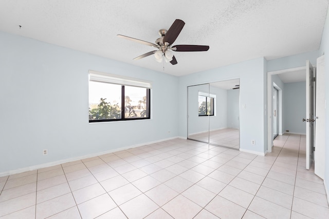 unfurnished bedroom featuring ceiling fan, light tile patterned floors, a textured ceiling, and a closet