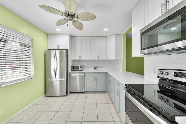 kitchen featuring sink, ceiling fan, appliances with stainless steel finishes, white cabinets, and light tile patterned flooring