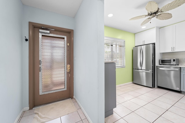 kitchen with stainless steel appliances, white cabinetry, light tile patterned floors, and ceiling fan