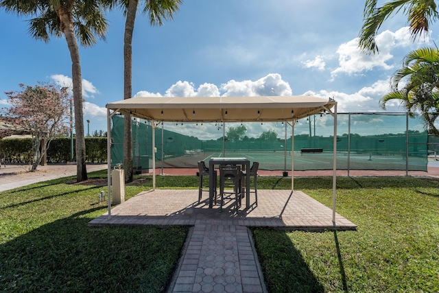 view of home's community featuring tennis court and a lawn