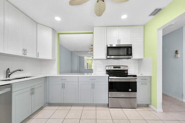 kitchen with gray cabinets, light tile patterned flooring, appliances with stainless steel finishes, sink, and ceiling fan