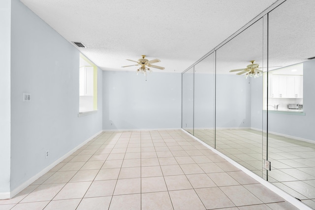 spare room featuring ceiling fan, a textured ceiling, and light tile patterned floors