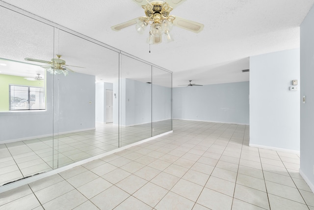 tiled empty room featuring ceiling fan and a textured ceiling