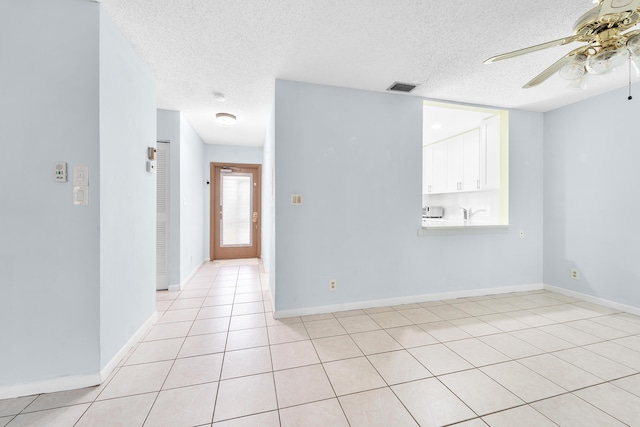 tiled empty room featuring a textured ceiling and ceiling fan