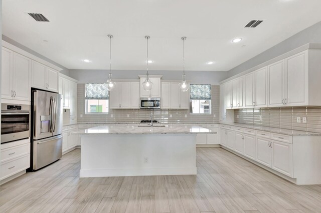 kitchen with stainless steel appliances, backsplash, visible vents, and white cabinetry