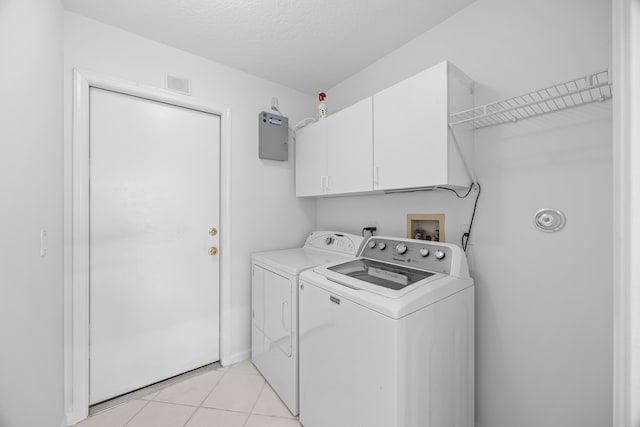 laundry room with cabinets, a textured ceiling, washer and dryer, and light tile patterned floors