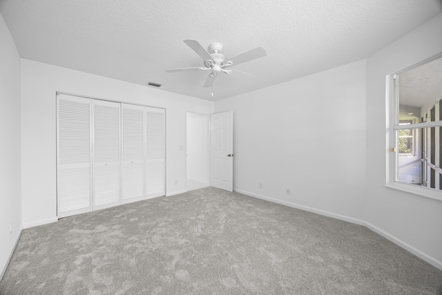 unfurnished bedroom featuring ceiling fan, carpet flooring, a textured ceiling, and a closet