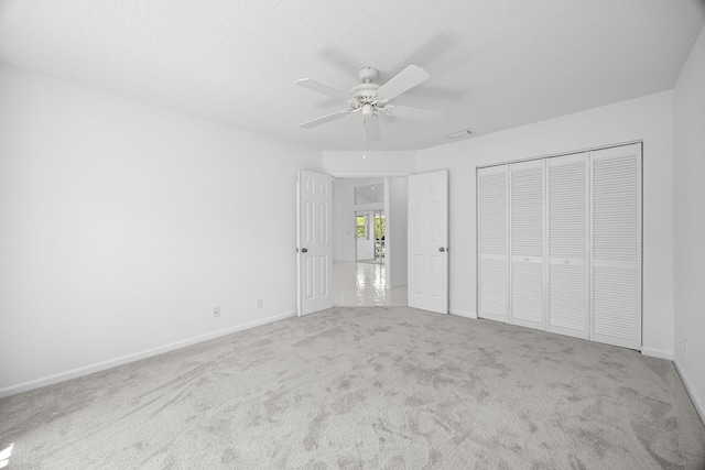 unfurnished bedroom with ceiling fan, carpet floors, a closet, and a textured ceiling