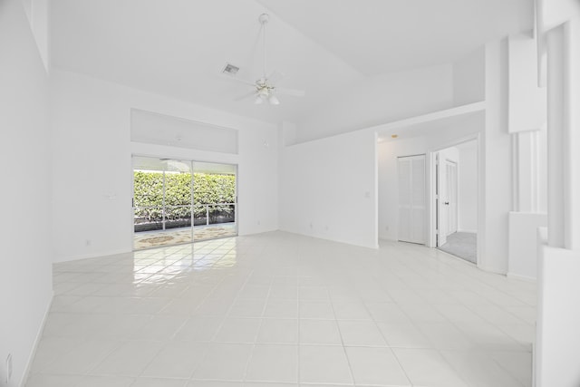 tiled empty room with ceiling fan and high vaulted ceiling